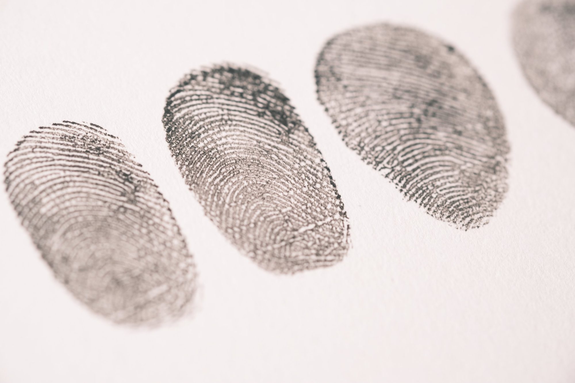 Close-up of three black fingerprint impressions on white paper.